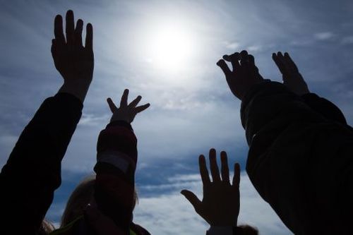 Nuoret kohottavat kätensä kohti taivasta.