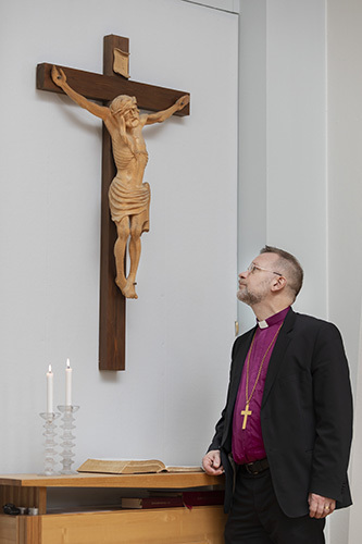 Piispa Jari Jolkkonen katsoo seinällä olevaa krusifiksiä