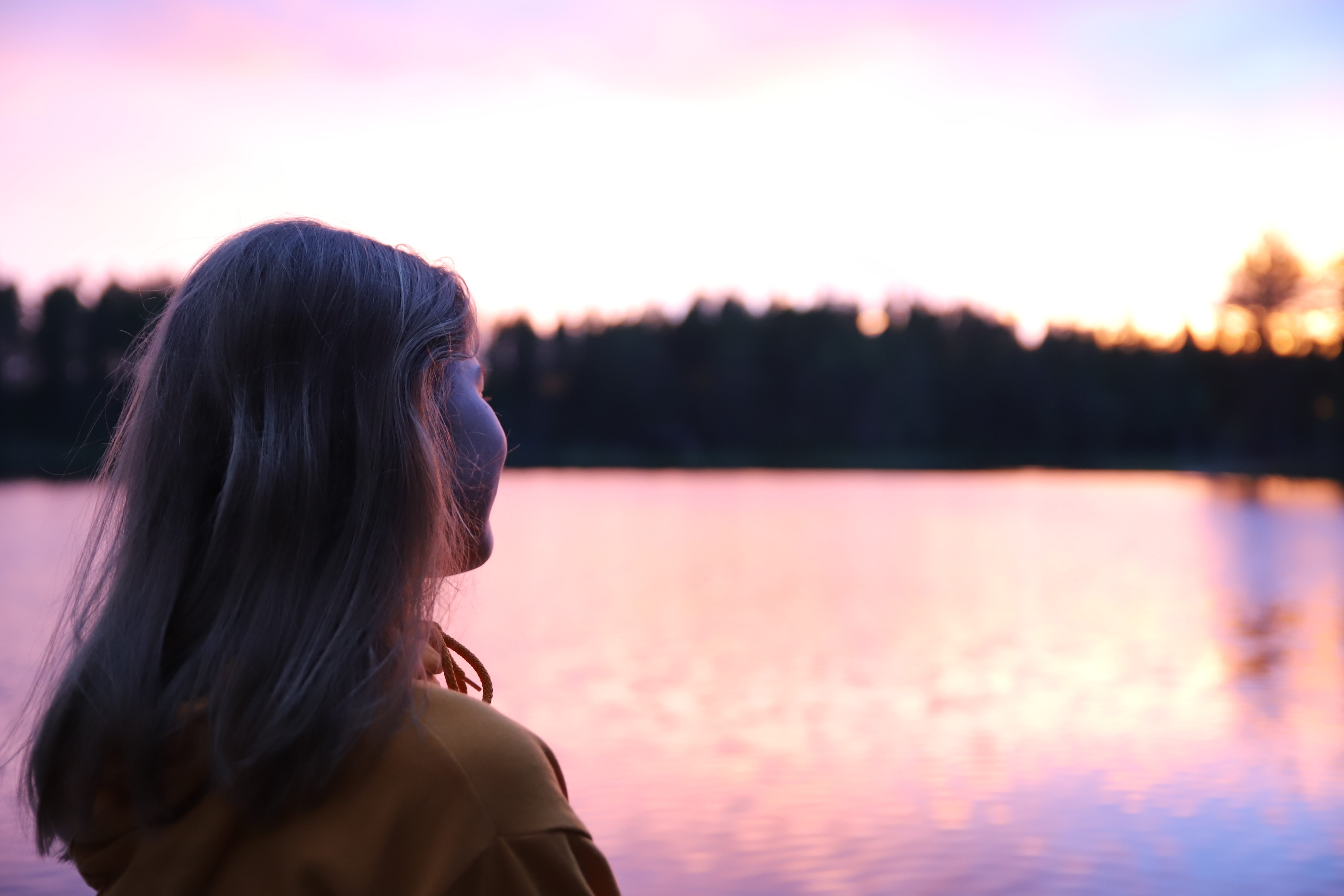 Kaunis vaaleanpunainen auringonlasku, rippikoululainen katsoo kaihoisasti Joutenlammelle